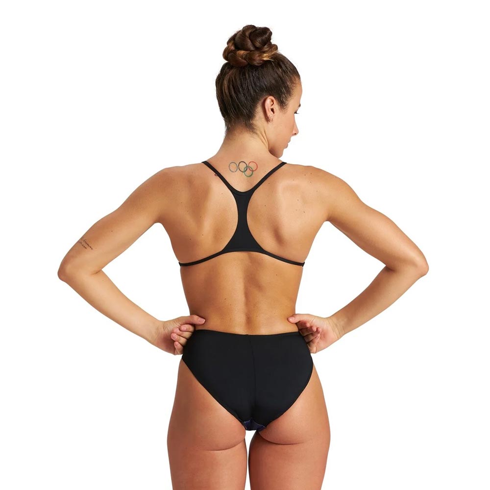 Back view of a woman wearing a black arena swimsuit with thin back straps.