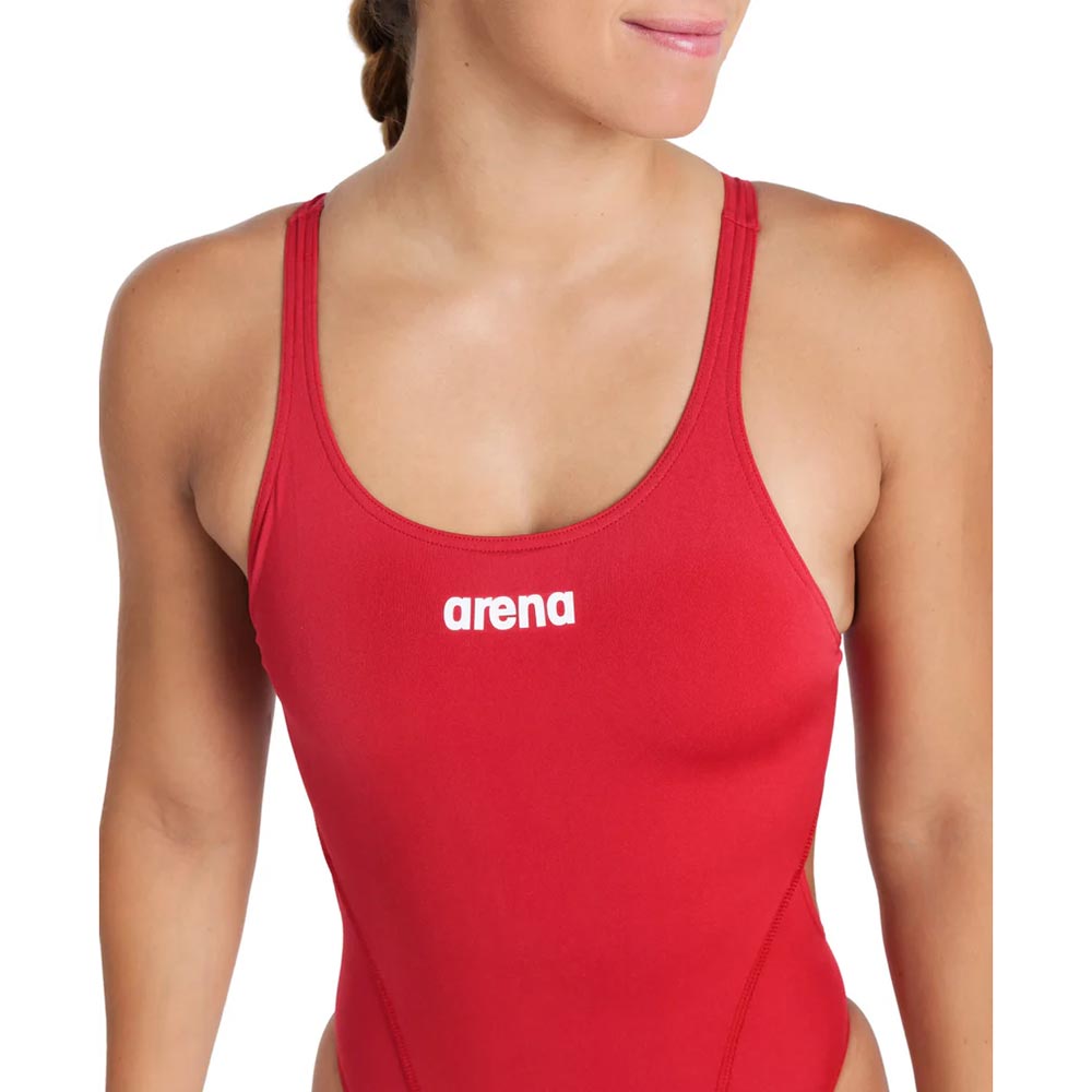 Close up of a woman wearing a red arena swimsuit with arena logo printed in white.