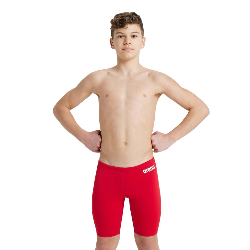 A boy wearing the arena boys team swim jammer in red.