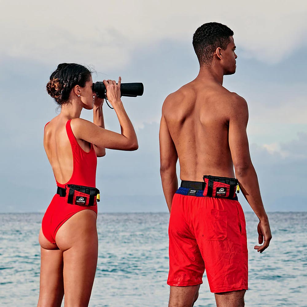 Two lifeguards wearing the Restube Lifeguard Water Rescue Buoys around their waists.