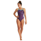 Woman wearing a purple coloured arena swimsuit with cyan straps.