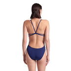 A back view of a woman wearing the arena lace one piece swimsuit in navy colour.