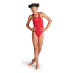 A girl posing in a red arena girls team swimsuit.