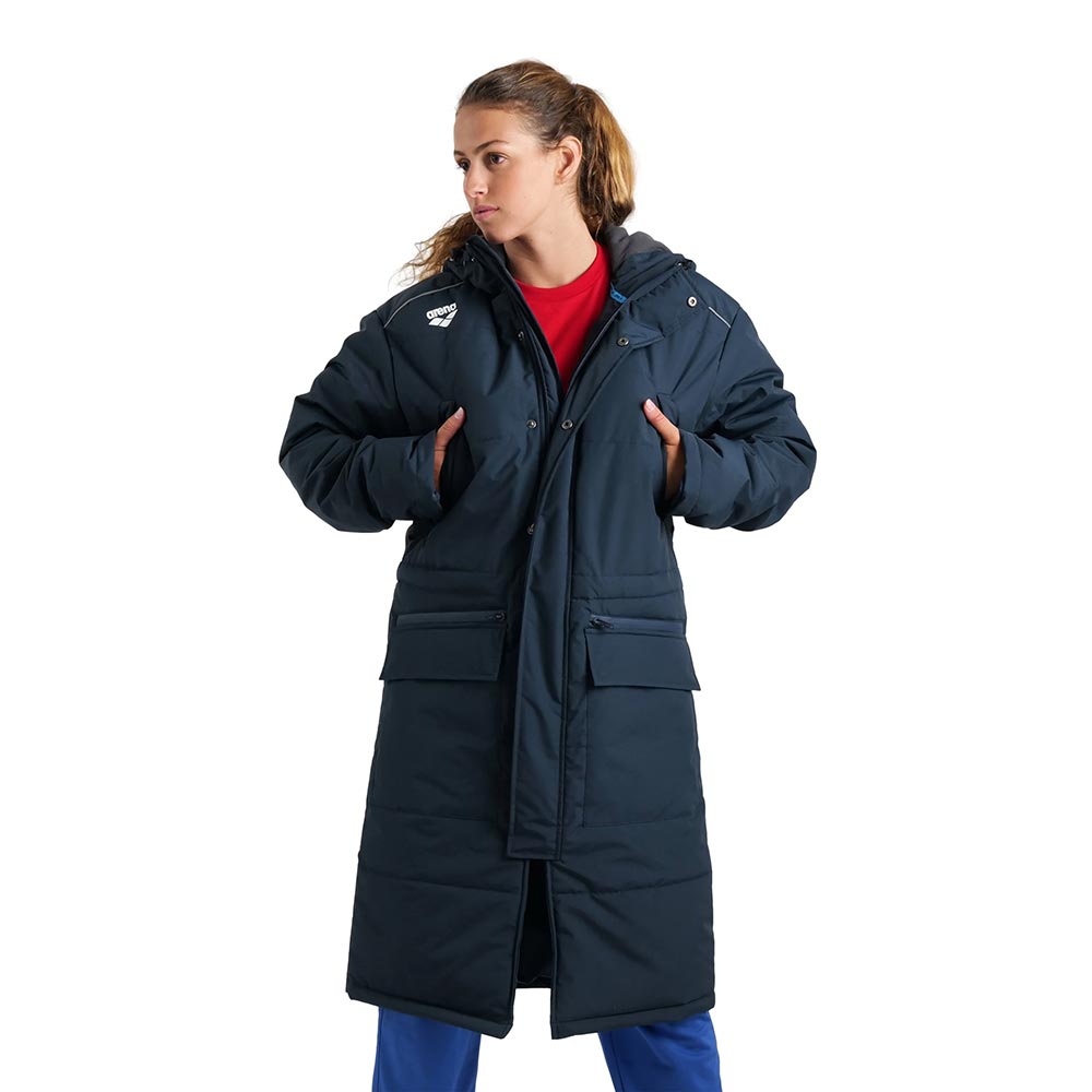 Arena unisex navy blue long padded parka jacket with hood, worn by a woman.