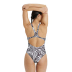 Back view of a woman wearing a black and white patterned one piece swimsuit.