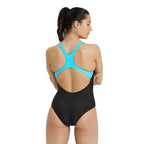 Back view of a woman wearing an area one piece swimsuit with cyan straps.