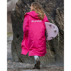 Pink Dryrobe Advance Adults Change Robe with hood, worn by a woman holding a surfboard on a beach