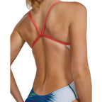 TYR Women's Bravura Cutoutfit Swimsuit: Back view of a woman in a blue, white, and green patterned swimsuit with a coral-coloured strap detail